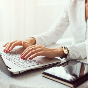 Woman working in home office hand on keyboard close up