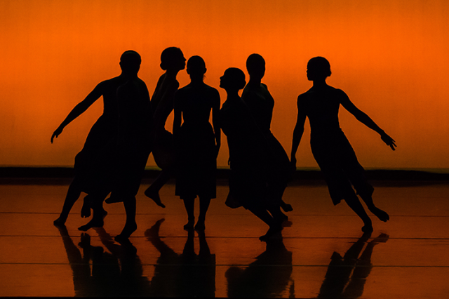 dancers in silhouette on an orange background