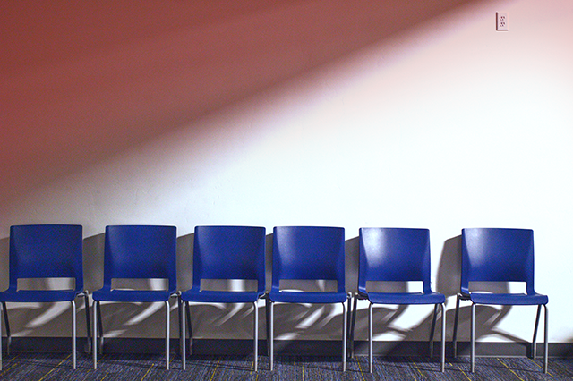 row of empty blue chairs against a white and red background